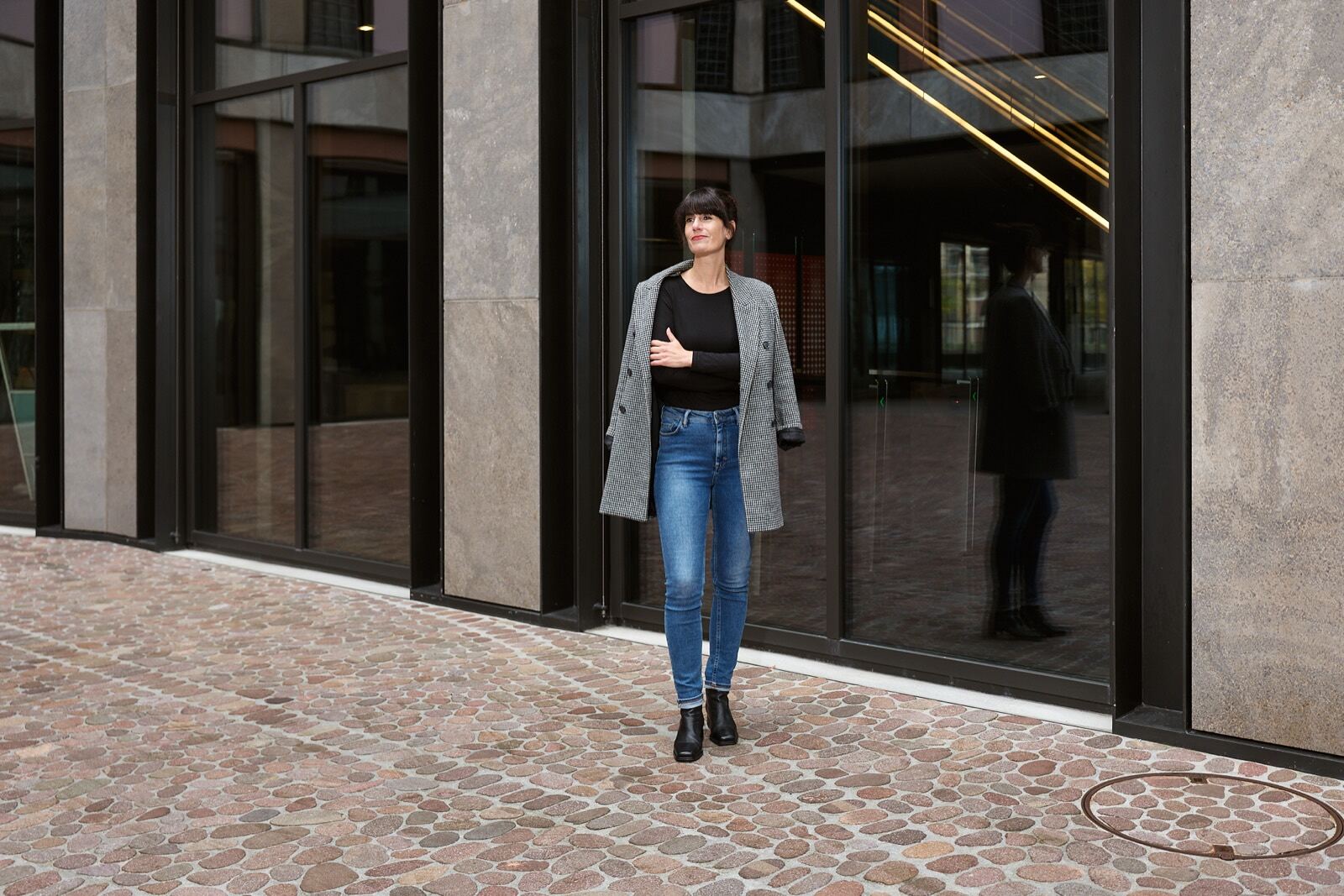 Elvira Häusler in hellem Mantel vor einer Glasfassade.